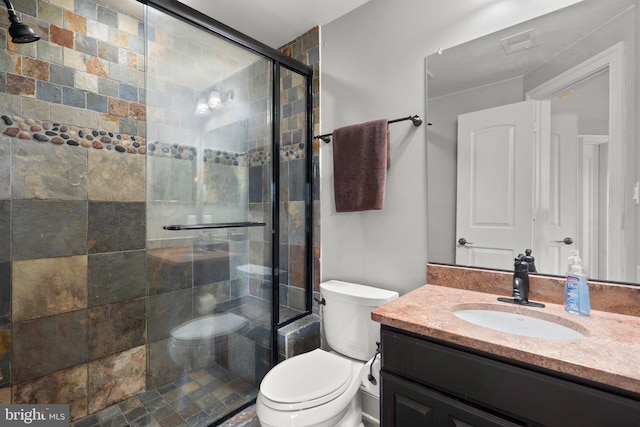 bathroom with a shower with door, vanity, and toilet