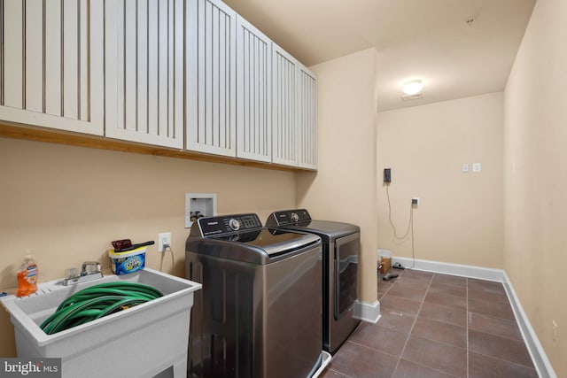 laundry area featuring washing machine and clothes dryer, sink, cabinets, and dark tile patterned flooring