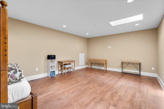 misc room with wood-type flooring and a skylight