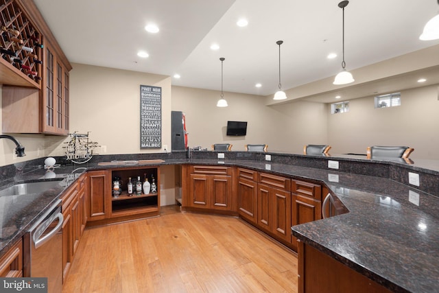 kitchen featuring dark stone countertops, sink, pendant lighting, and light wood-type flooring