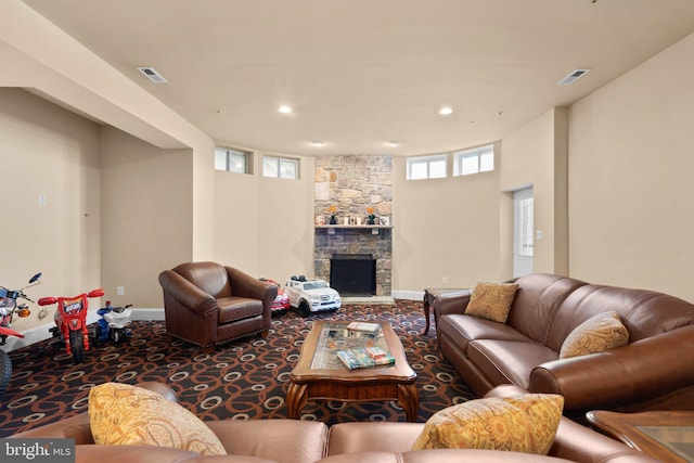 living room with carpet, a stone fireplace, and a healthy amount of sunlight