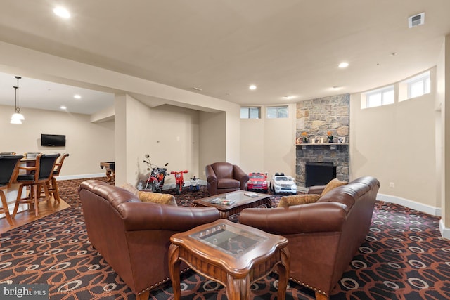 living room featuring dark colored carpet and a stone fireplace