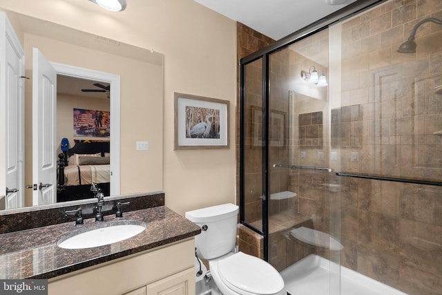 bathroom with ceiling fan, vanity, an enclosed shower, and toilet