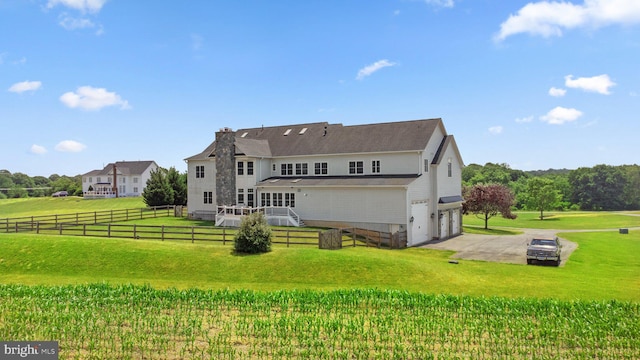 rear view of house featuring a wooden deck, a yard, a rural view, and a garage