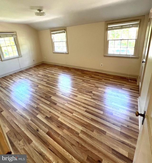 unfurnished room with light wood-type flooring and vaulted ceiling