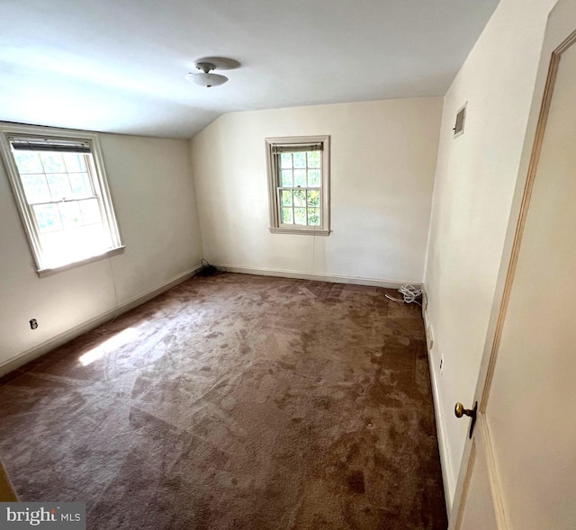 unfurnished room with vaulted ceiling and dark carpet