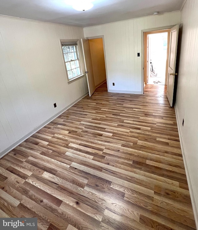 unfurnished room featuring wood walls, crown molding, and hardwood / wood-style flooring