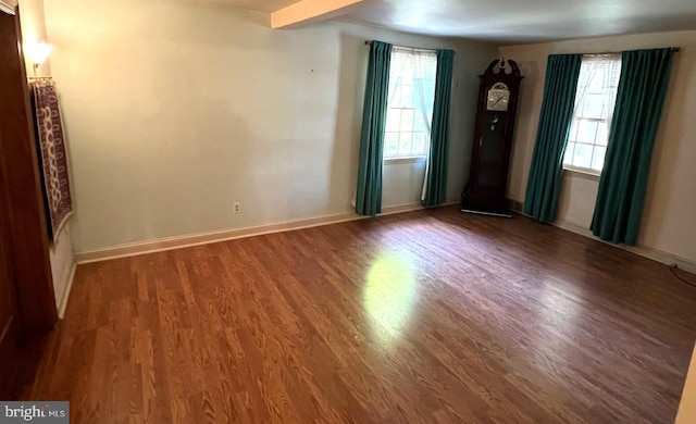 empty room featuring dark wood-type flooring and a healthy amount of sunlight