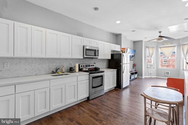 kitchen featuring white cabinets, appliances with stainless steel finishes, ceiling fan, and dark wood-type flooring