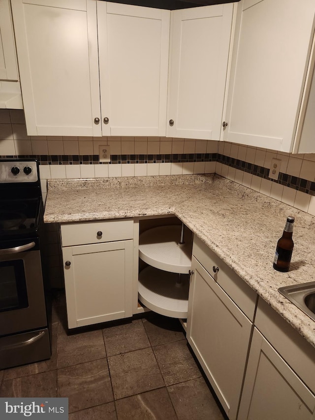 kitchen featuring stainless steel range with electric cooktop, decorative backsplash, light stone counters, white cabinetry, and extractor fan