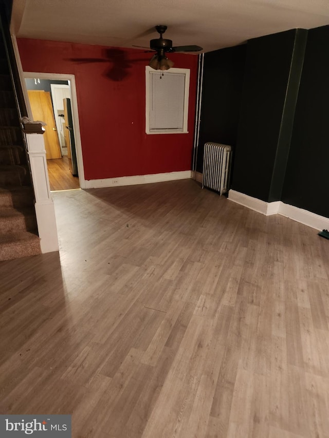 unfurnished room featuring ceiling fan, light wood-type flooring, and radiator