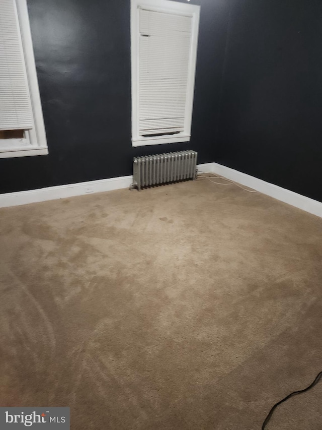 carpeted empty room with radiator heating unit