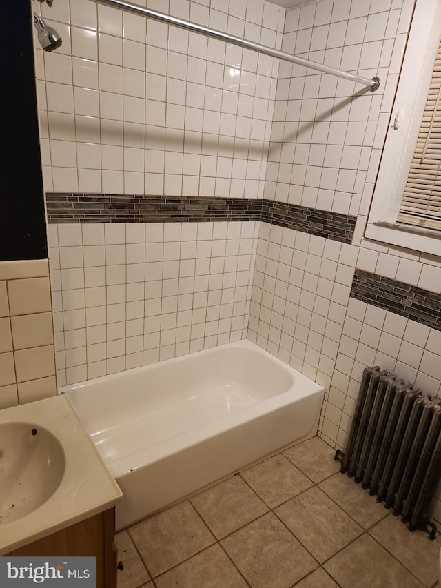 bathroom featuring radiator, tile patterned flooring,  shower combination, vanity, and tile walls