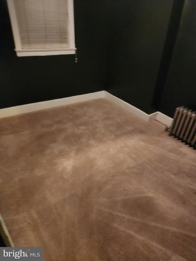 empty room with carpet flooring and radiator heating unit