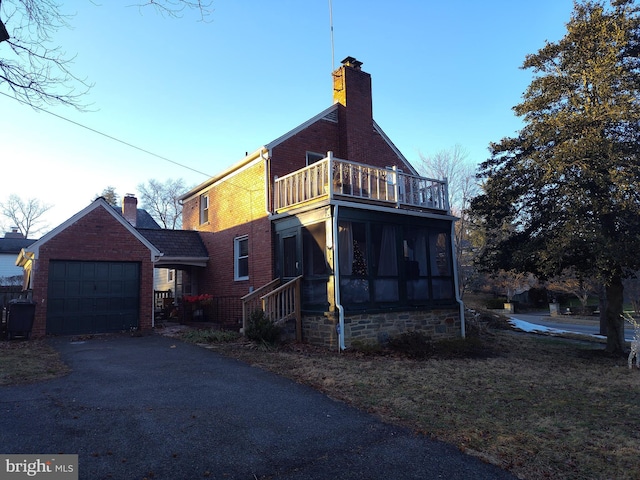 view of side of home with a balcony, a garage, and a sunroom