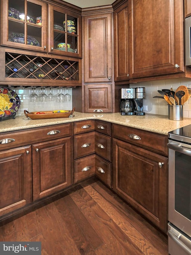 kitchen with dark hardwood / wood-style floors, tasteful backsplash, stainless steel range with electric stovetop, and light stone counters