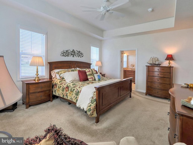 carpeted bedroom with connected bathroom, ceiling fan, and a tray ceiling