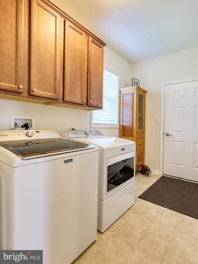 washroom with independent washer and dryer, cabinets, and light tile floors