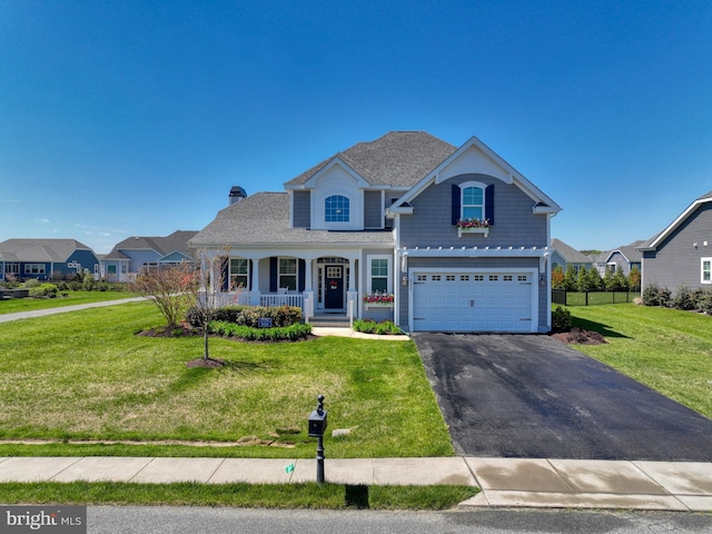 view of front of home featuring a front yard, a garage, and covered porch