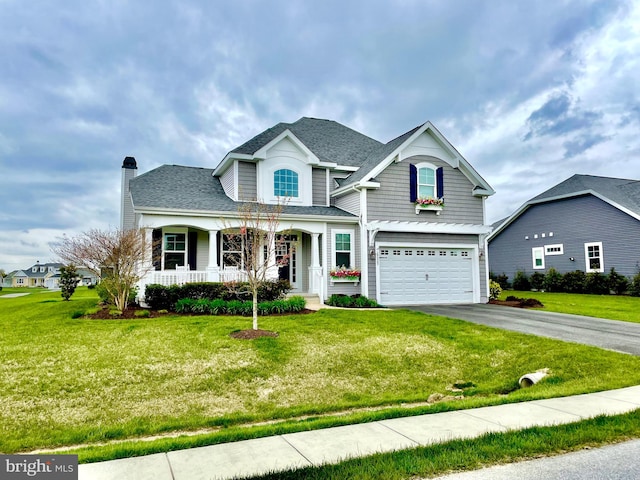 view of front of property with a front lawn, covered porch, and a garage