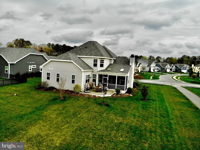 back of property featuring a yard, a sunroom, and a patio