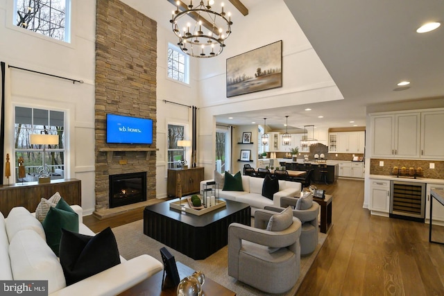 living room featuring a high ceiling, a fireplace, hardwood / wood-style floors, and beverage cooler