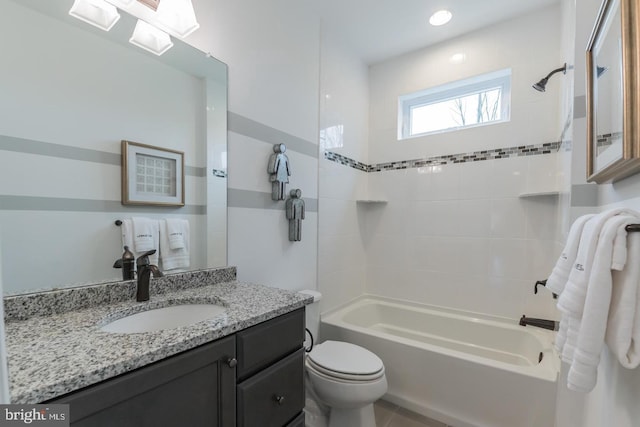 full bathroom with tiled shower / bath, vanity with extensive cabinet space, and toilet