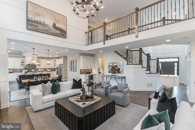 living room with ornamental molding, an inviting chandelier, dark hardwood / wood-style flooring, and a towering ceiling