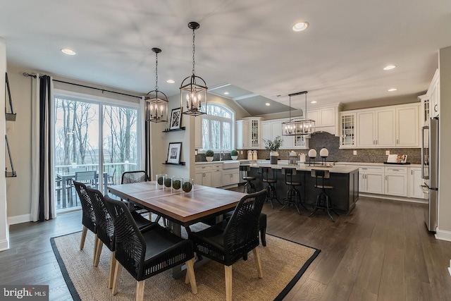 dining room featuring dark wood-type flooring, a notable chandelier, and lofted ceiling