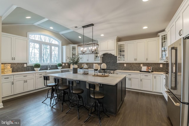 kitchen featuring a center island, dark wood-type flooring, decorative light fixtures, and vaulted ceiling