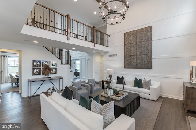 living room with dark wood-type flooring, a notable chandelier, and a high ceiling