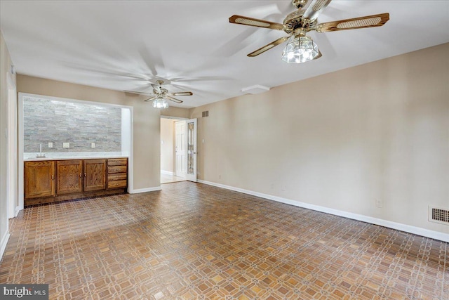 unfurnished living room featuring ceiling fan and sink