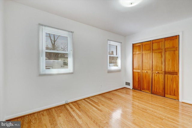 unfurnished bedroom with light wood-type flooring and a closet