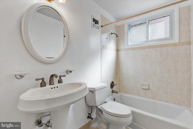 bathroom featuring toilet and tiled shower / bath