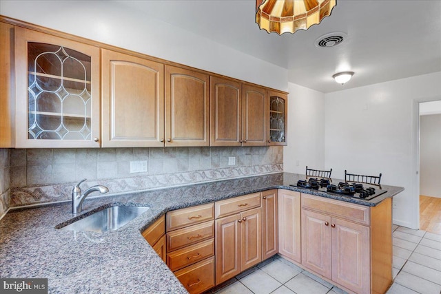 kitchen with kitchen peninsula, gas cooktop, sink, stone counters, and light tile patterned flooring