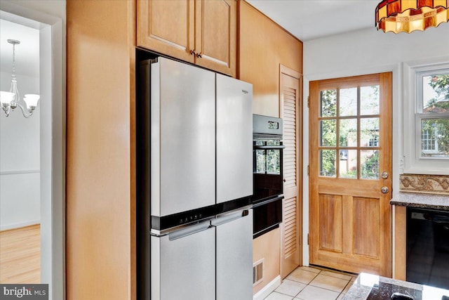 kitchen featuring black appliances, light tile patterned floors, pendant lighting, light brown cabinets, and a notable chandelier