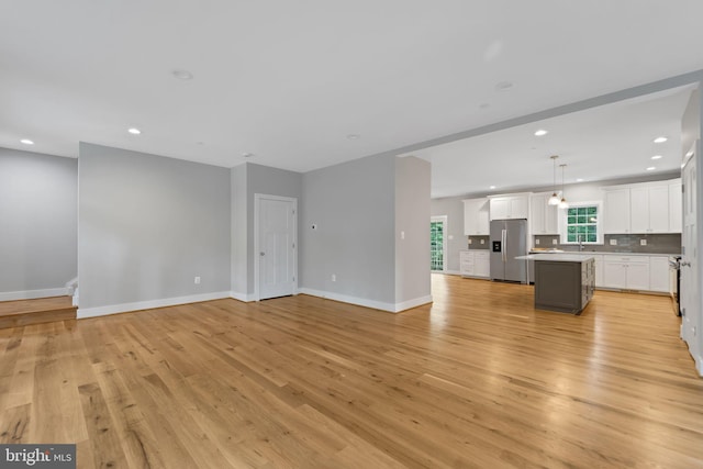 unfurnished living room with sink and light wood-type flooring