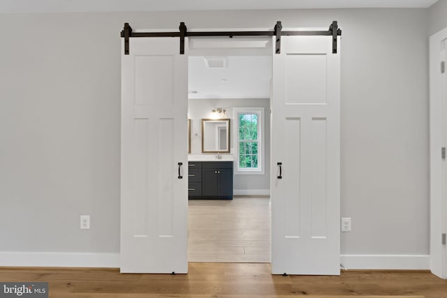 hall with sink, a barn door, and light wood-type flooring