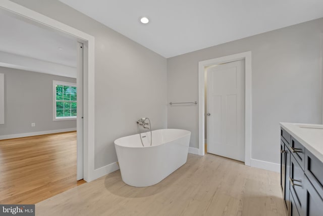 bathroom featuring vanity, a bath, and hardwood / wood-style floors