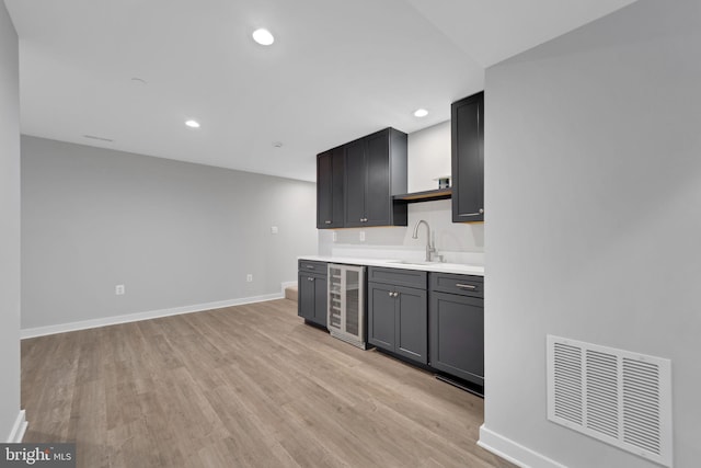 kitchen featuring wine cooler, light hardwood / wood-style floors, and sink