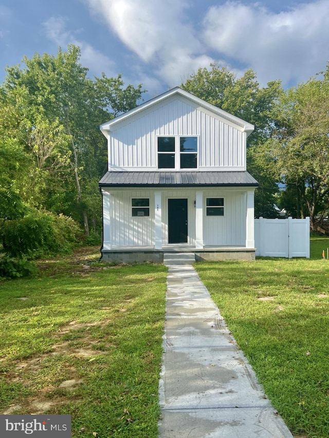 view of front of property with metal roof, a porch, fence, board and batten siding, and a front yard