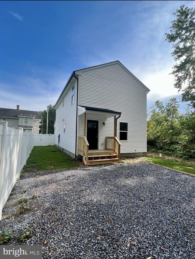 back of property with fence and driveway