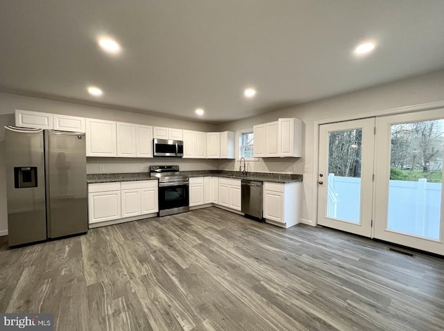 kitchen with sink, hardwood / wood-style floors, stainless steel appliances, and white cabinets