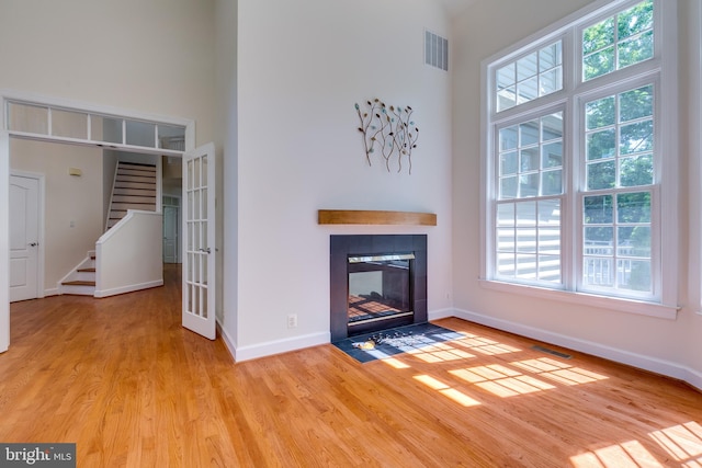 unfurnished living room with a high ceiling, light hardwood / wood-style floors, and a fireplace