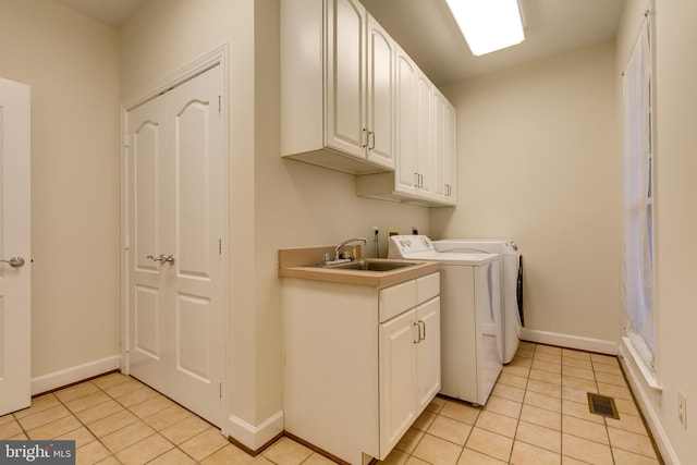 laundry room with cabinets, sink, light tile floors, and washing machine and clothes dryer