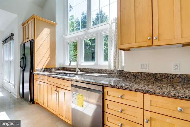 kitchen with dark stone counters, light brown cabinetry, light tile floors, sink, and appliances with stainless steel finishes