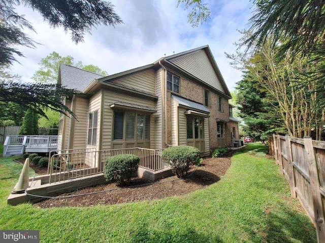 view of side of home with central AC unit and a lawn