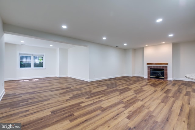 unfurnished living room with wood-type flooring and a tile fireplace