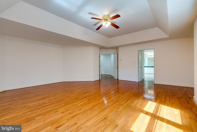 unfurnished room featuring ceiling fan, a raised ceiling, and light hardwood / wood-style floors