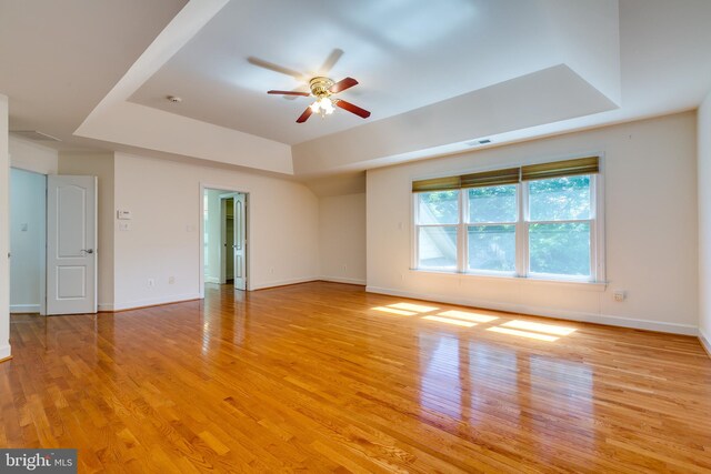 spare room featuring light hardwood / wood-style floors, ceiling fan, and a raised ceiling